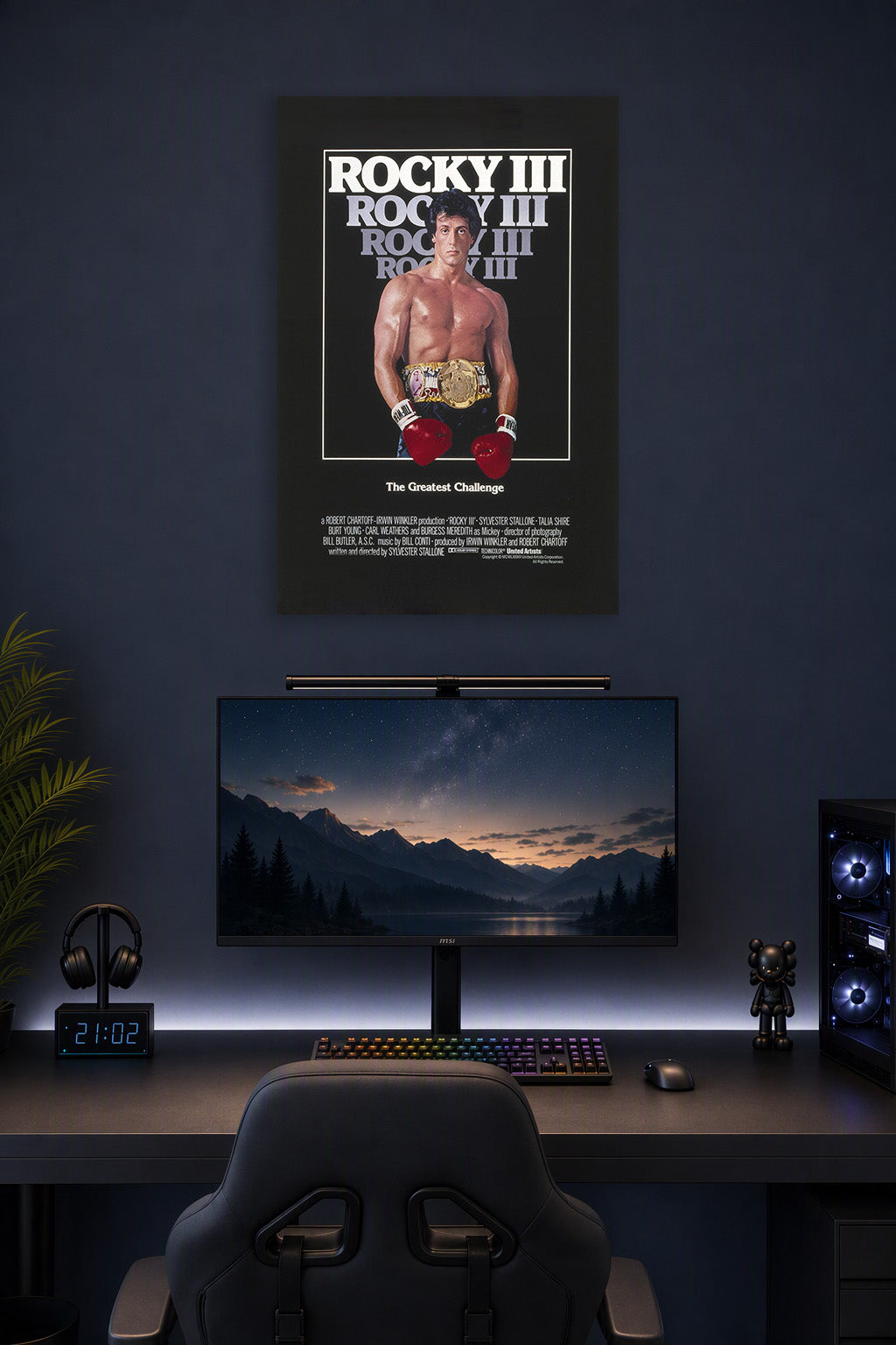 Rocky III Sylvester Stallone in a gaming desk setup above a monitor.