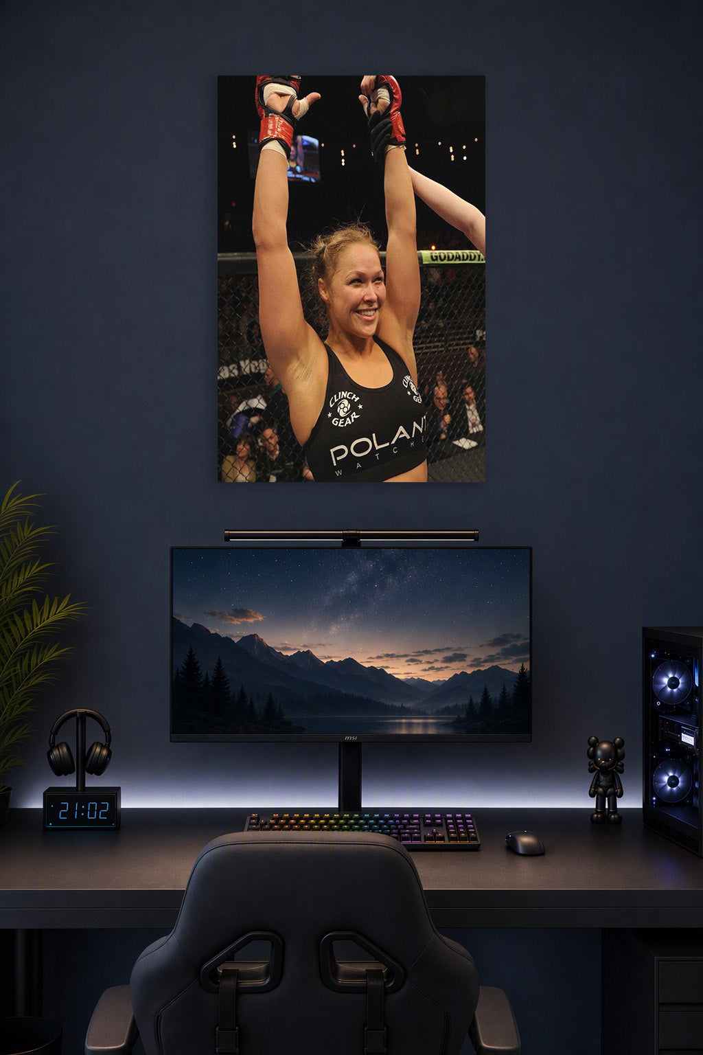 Ronda Rousey in a gaming desk setup above a monitor.