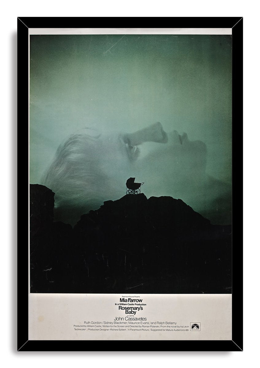 Rosemary's Baby framed wall art print presents a green-tinted woman’s profile and baby carriage silhouette over a black rocky landscape.
