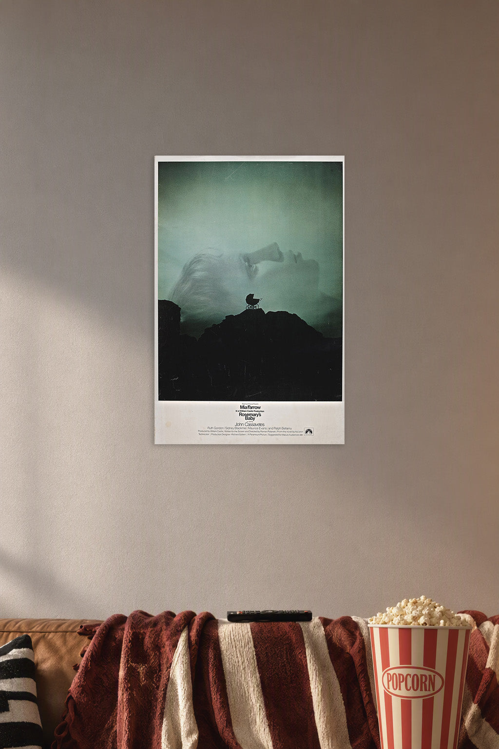 Rosemary's Baby Movie Poster in a cozy movie room above a brown sofa with popcorn.
