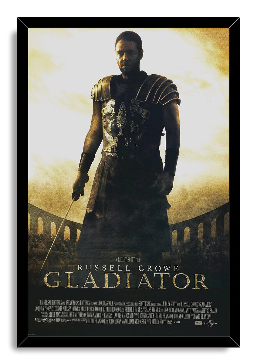 Framed Gladiator wall art print featuring Russell Crowe in dark Roman armor, sword in hand, against a sunlit arena.