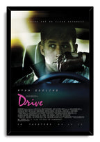 Drive movie poster wall art print in a black frame, featuring Ryan Gosling in a car with a leather glove and pink title text.