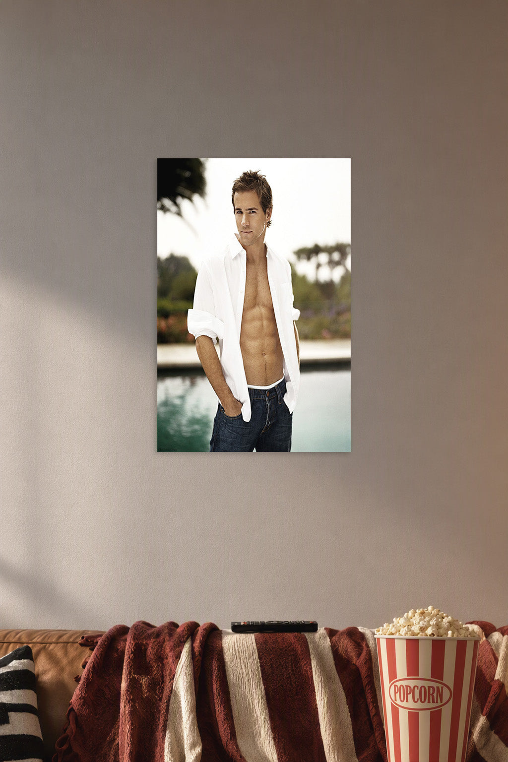 Ryan Reynolds in a cozy movie room above a brown sofa with popcorn.