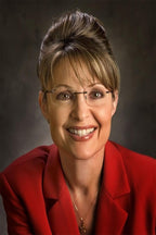 Sarah Palin wall art print features a smiling close-up portrait in rimless glasses and a vivid red blazer against gray.