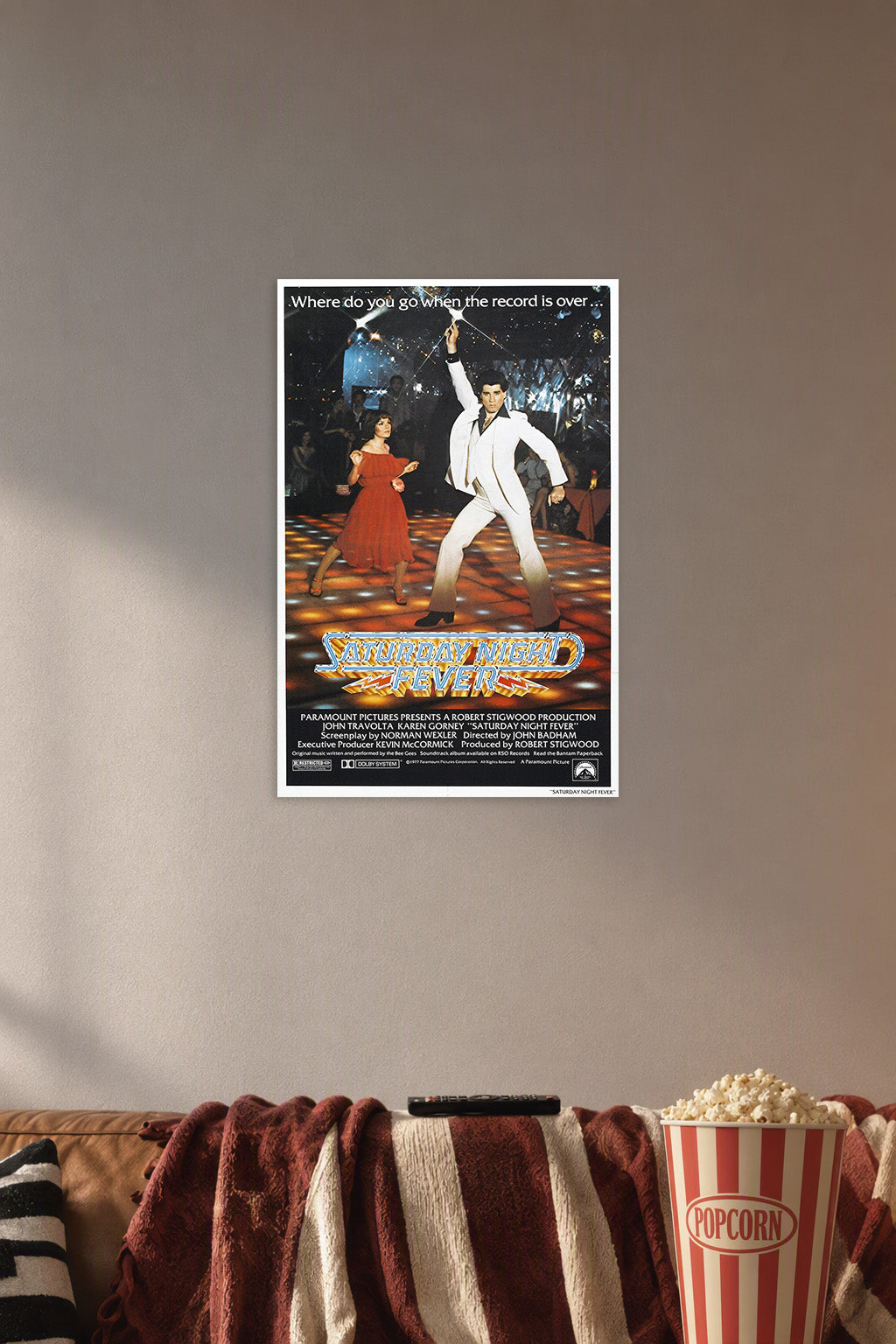 Saturday Night Fever John Travolta in a cozy movie room above a brown sofa with popcorn.