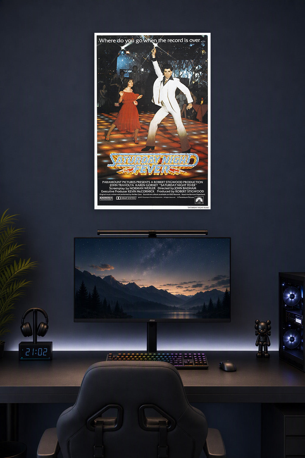 Saturday Night Fever John Travolta in a gaming desk setup above a monitor.