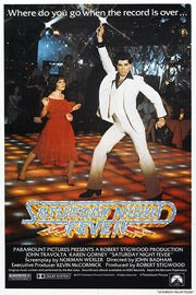Saturday Night Fever poster features John Travolta in a white suit dancing beside a woman in red on a glowing disco floor.