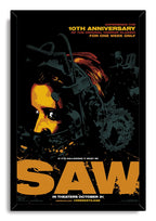 Saw movie framed wall art print in a black frame, with a yellow-orange face, reverse trap components, gears, and large orange lettering.