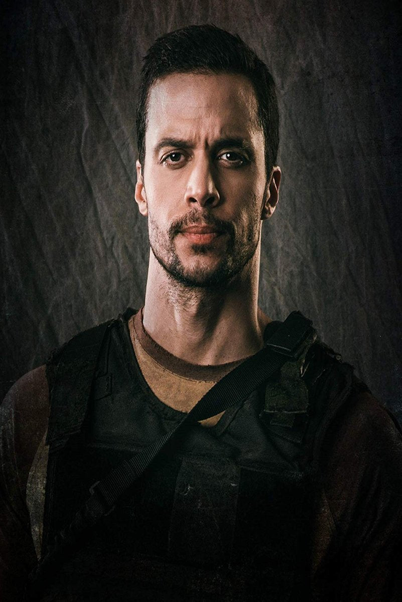 Tactical man wall art print with a stern bearded portrait, black vest and shoulder strap against a dark textured backdrop.
