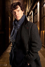 Sherlock Holmes wall art print portrays a dark-haired man in a charcoal coat and blue scarf standing in a warmly lit alley.