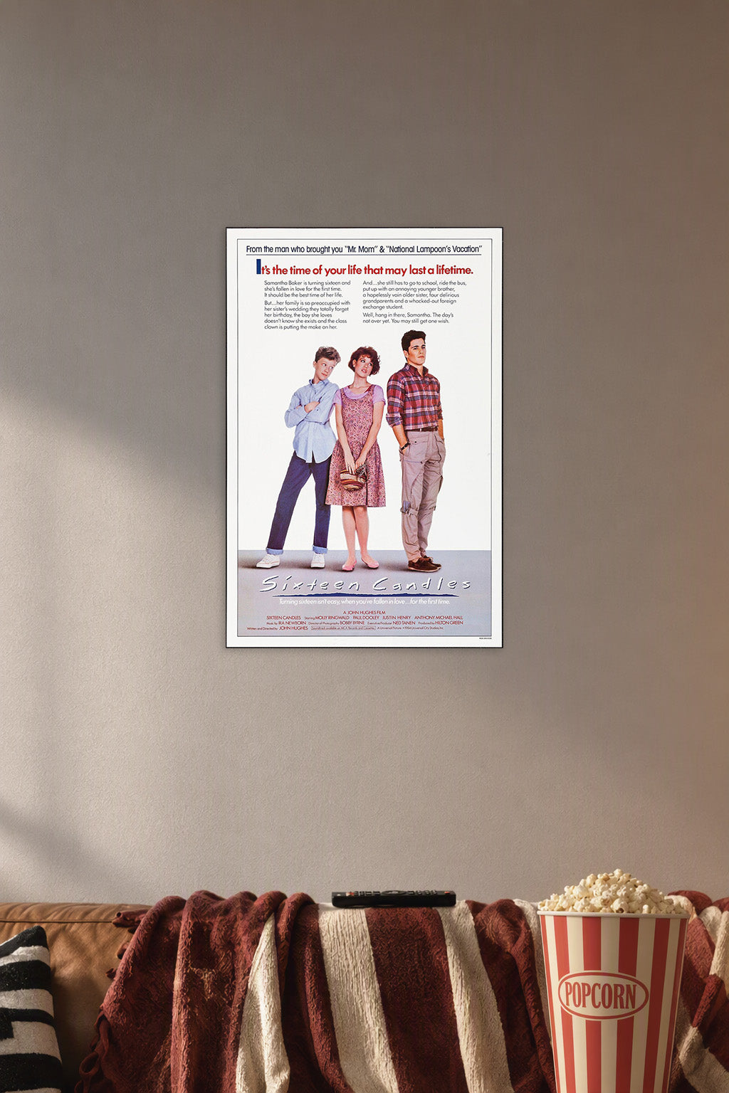 Sixteen Candles Movie Poster in a cozy movie room above a brown sofa with popcorn.