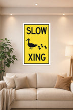 Slow Duck Crossing Sign in a bright living room above a beige sofa.