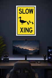 Slow Duck Crossing Sign in a gaming desk setup above a monitor.