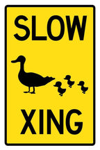 Slow Duck Crossing poster with bold black lettering and silhouettes of a mother duck with three ducklings on yellow.