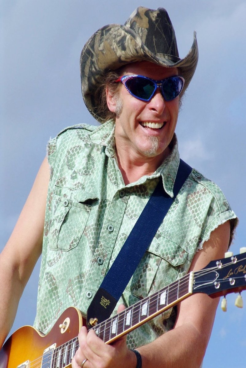 Guitarist wall art print featuring a smiling man in a camouflage cowboy hat and blue sunglasses playing a sunburst electric guitar against a pale blue sky.