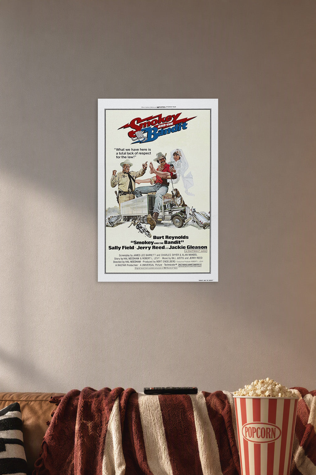 Smokey and the Bandit Movie Poster in a cozy movie room above a brown sofa with popcorn.