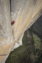 Rock climber wall art print depicts a person in a red shirt ascending a sheer tan cliff above a green forest valley.