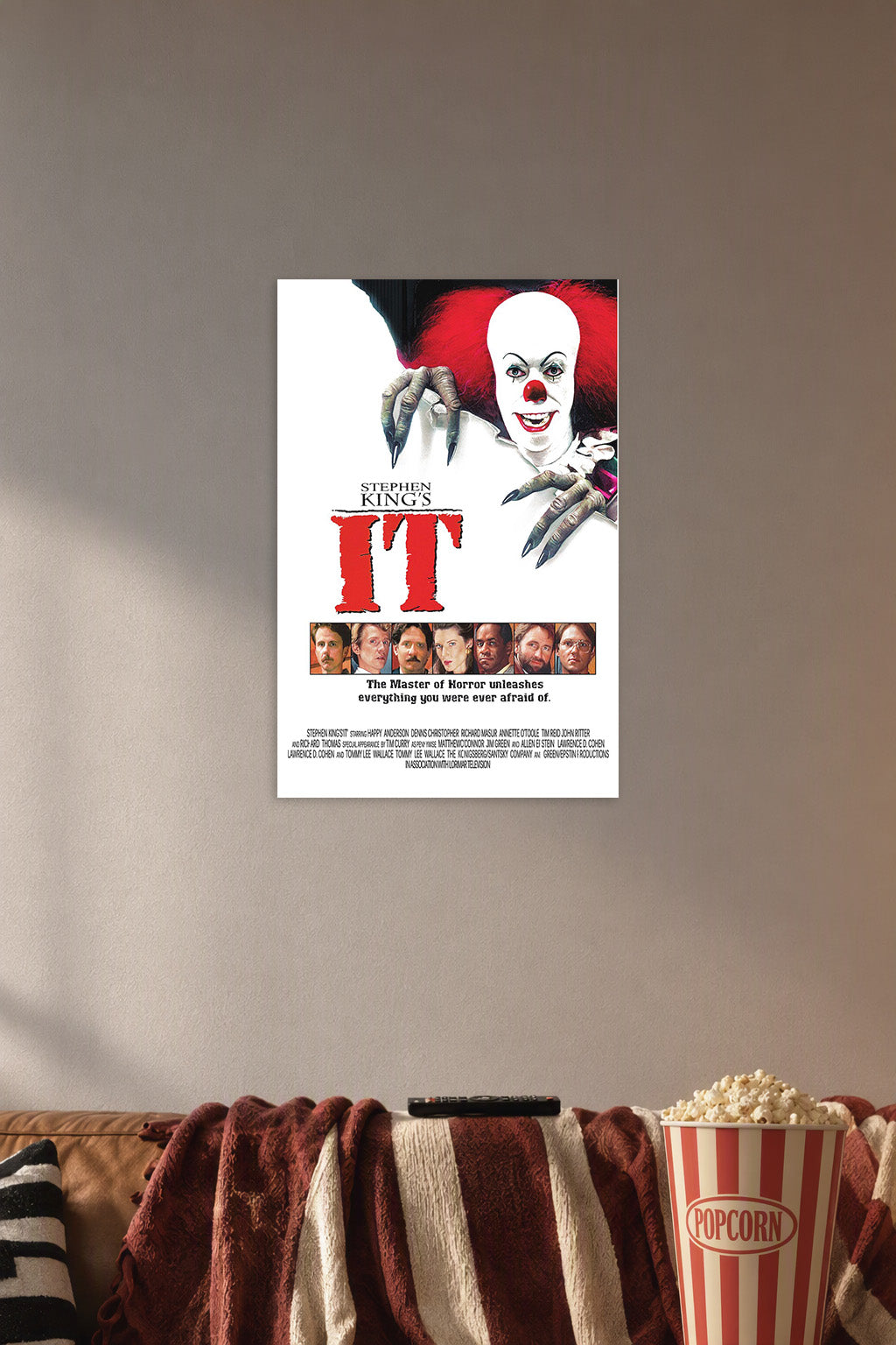 Stephen King's IT Pennywise in a cozy movie room above a brown sofa with popcorn.