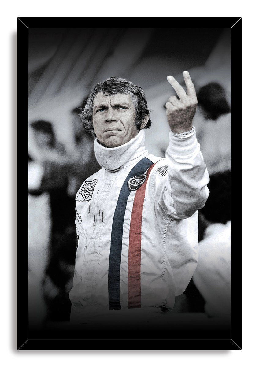 Steve McQueen framed wall art print depicts the racer holding up two fingers in a white suit against a blurred crowd.