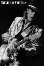 Stevie Ray Vaughan poster features a black-and-white performance portrait of the guitarist in a hat and shimmering jacket.