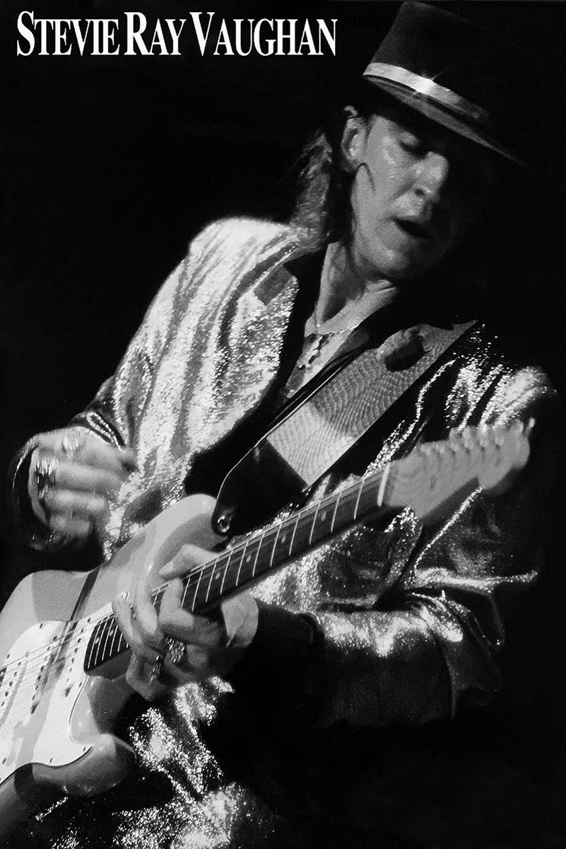 Stevie Ray Vaughan poster features a black-and-white performance portrait of the guitarist in a hat and shimmering jacket.