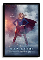 Supergirl framed wall art print presents the heroine in her blue and red costume against smoke, flying sparks, and bold title text.