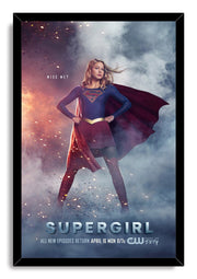 Supergirl framed wall art print presents the heroine in her blue and red costume against smoke, flying sparks, and bold title text.