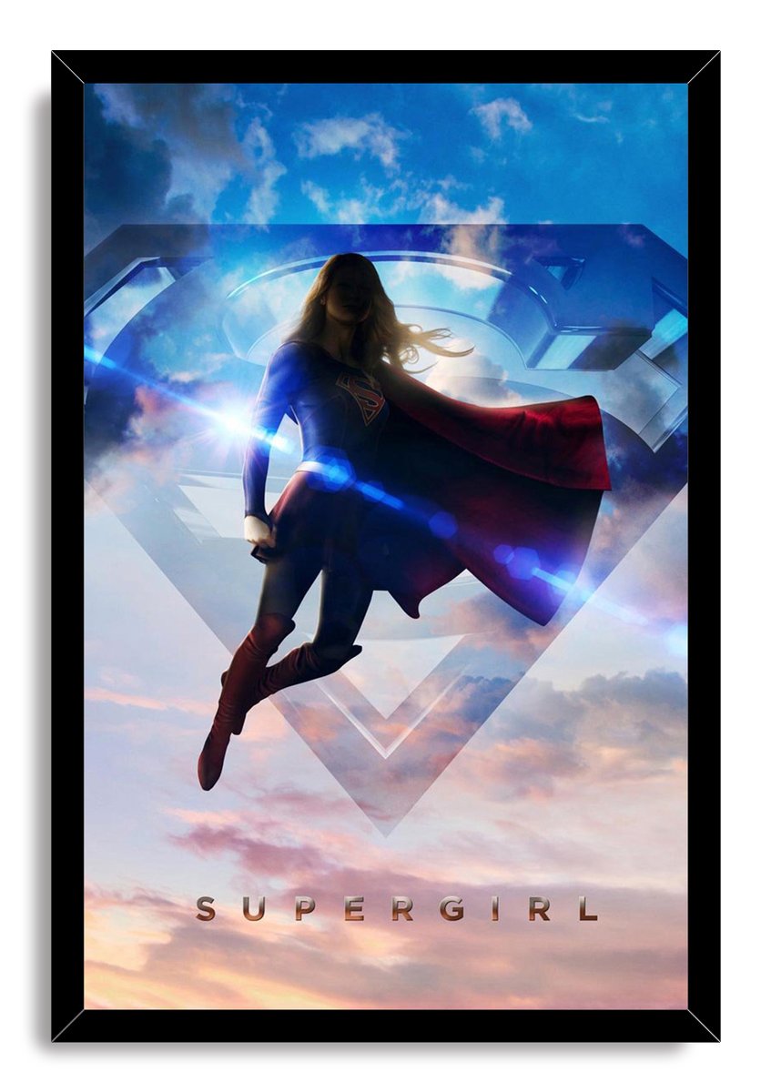 Supergirl framed wall art print presents the flying heroine in a blue suit and red cape against clouds and a large S symbol.