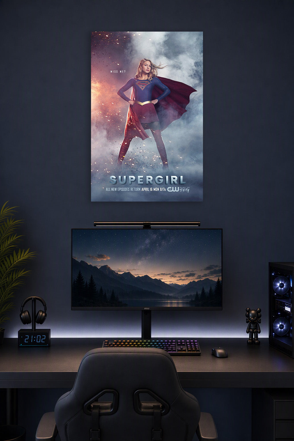 Supergirl in a gaming desk setup above a monitor.