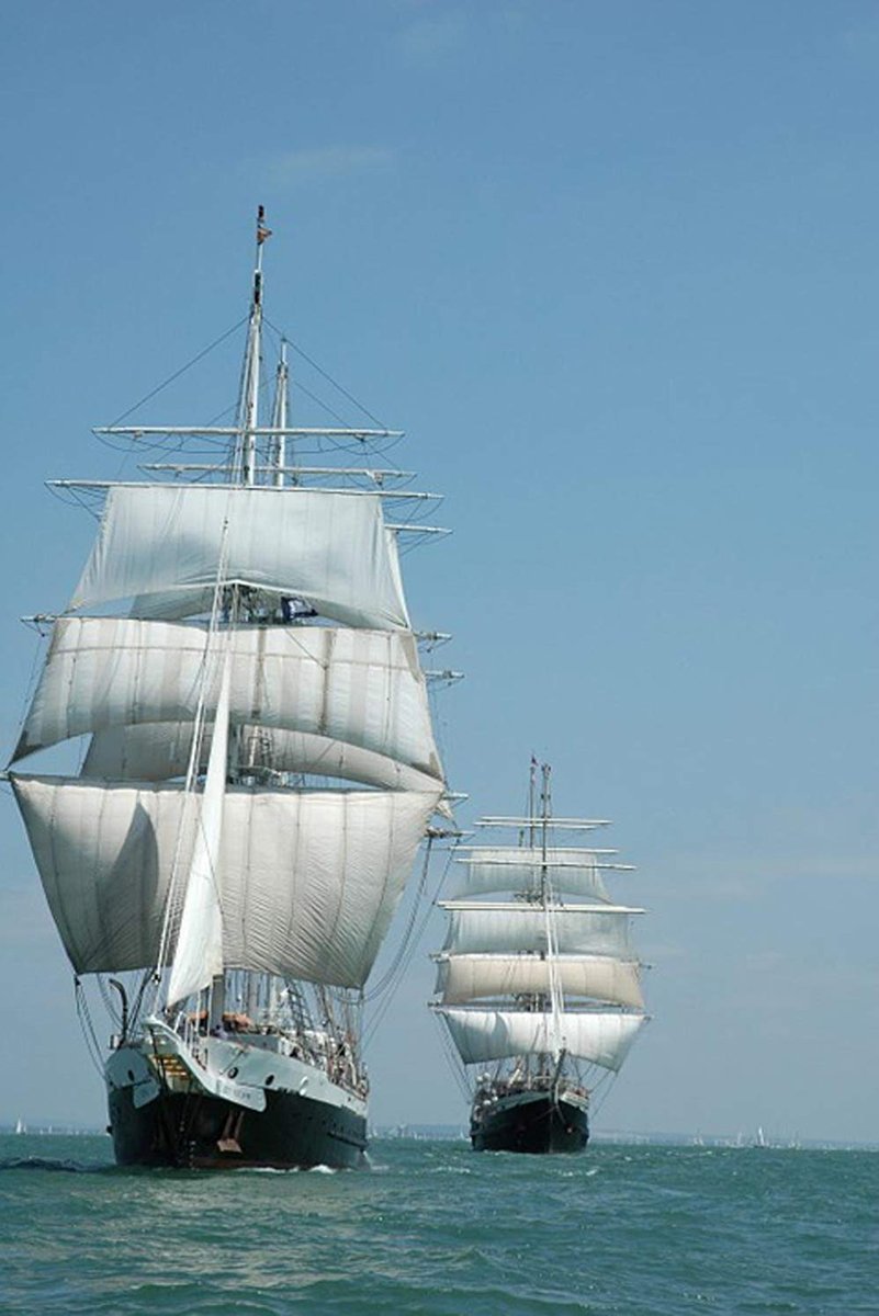 Tall ships wall art print with two black-hulled sailing vessels carrying full white sails across a rippled blue sea.