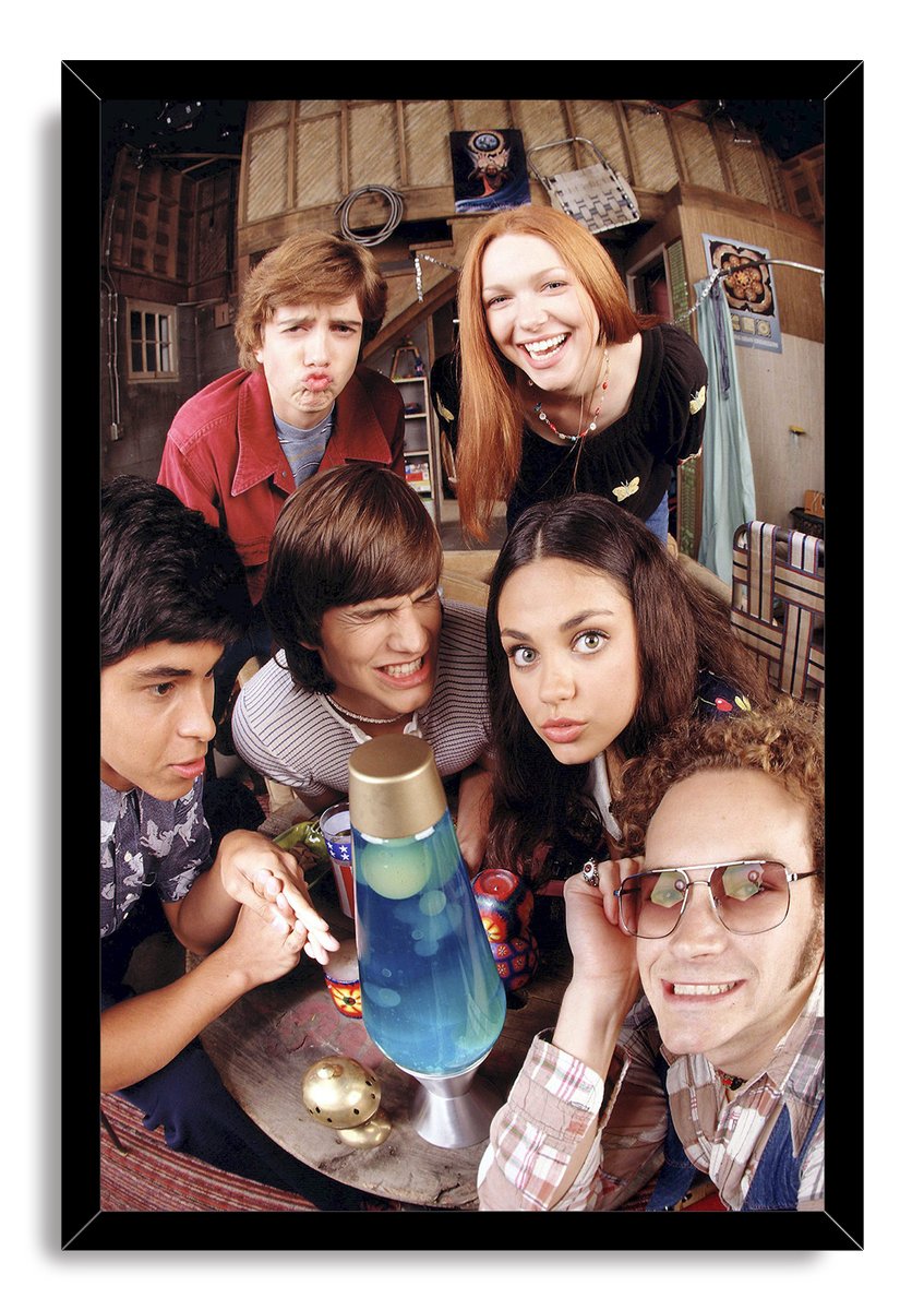 That '70s Show cast framed wall art print presents six friends gathered around a blue lava lamp in a glossy black frame.