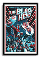 Framed The Black Keys poster presents two costumed heroes, a raised shield, a white guitar, and red laser beams.