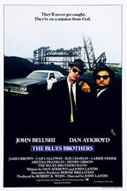 The Blues Brothers poster features two men in black suits, hats and sunglasses beside a police car in an industrial yard.