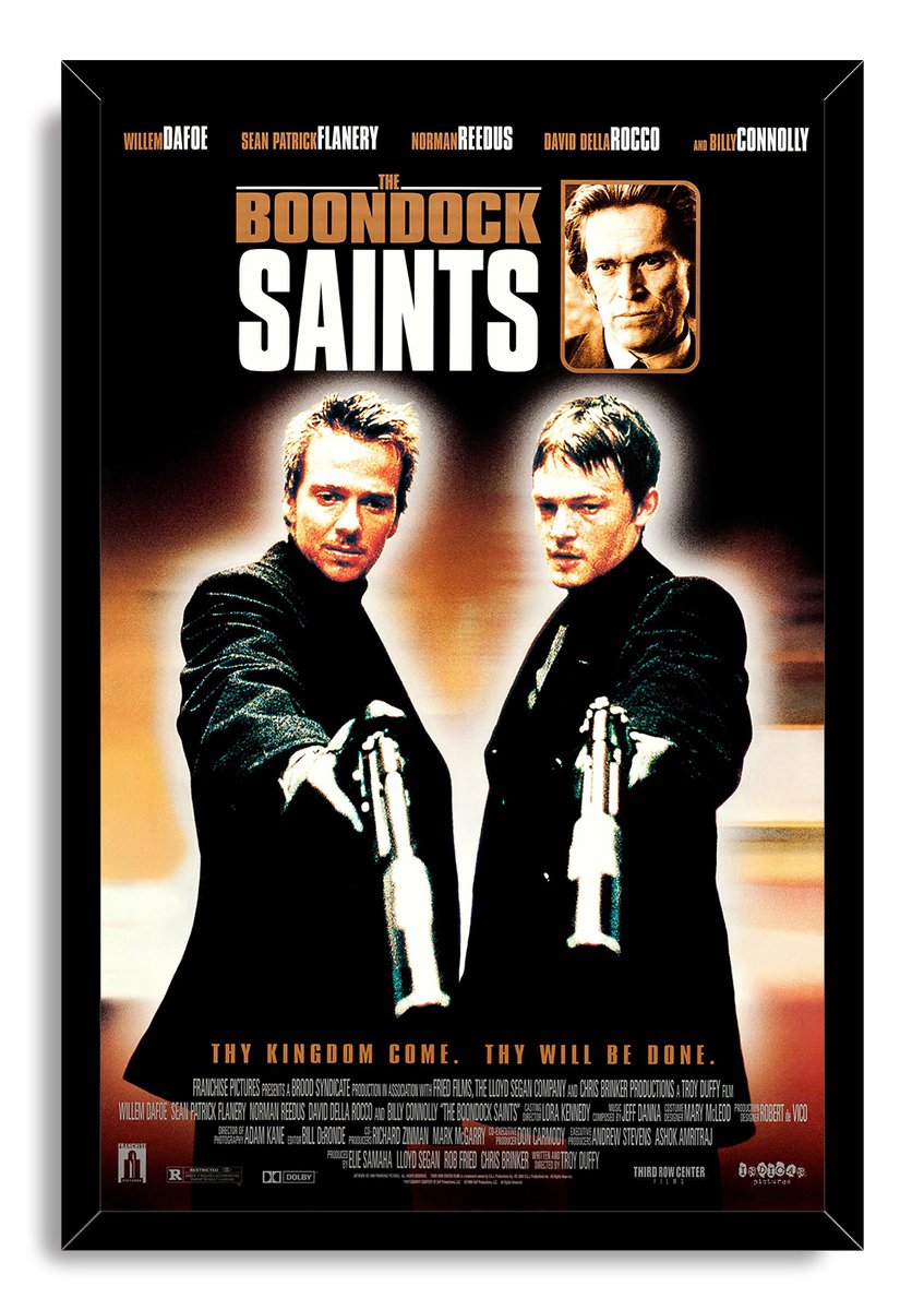The Boondock Saints framed wall art print features two men aiming guns, a sepia headshot, and a black mitered frame.