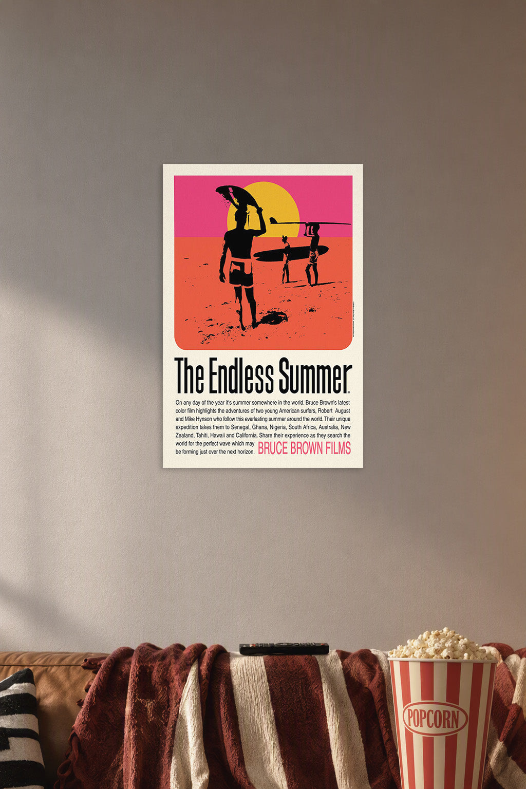 The Endless Summer Movie Poster in a cozy movie room above a brown sofa with popcorn.