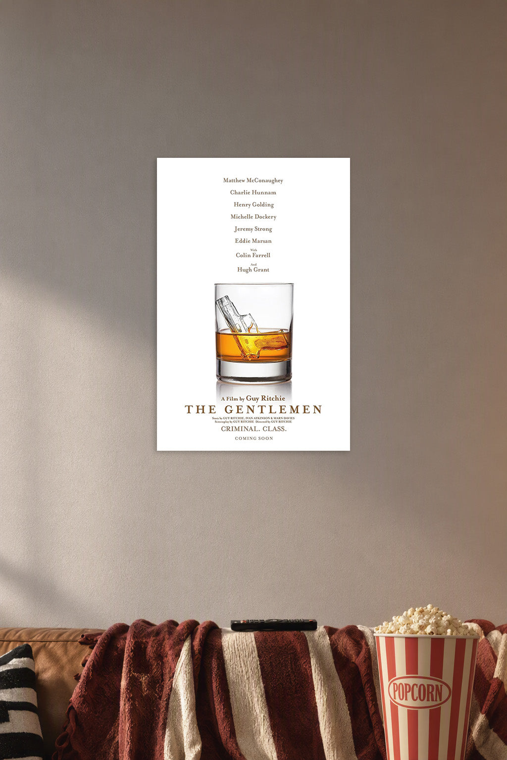 The Gentlemen Movie Poster in a cozy movie room above a brown sofa with popcorn.