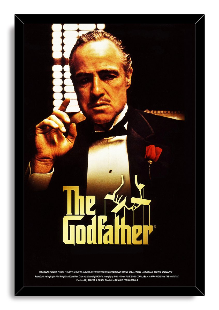 The Godfather framed wall art print presents Vito Corleone in warm shadow, black suit, red boutonniere, and gold typography.