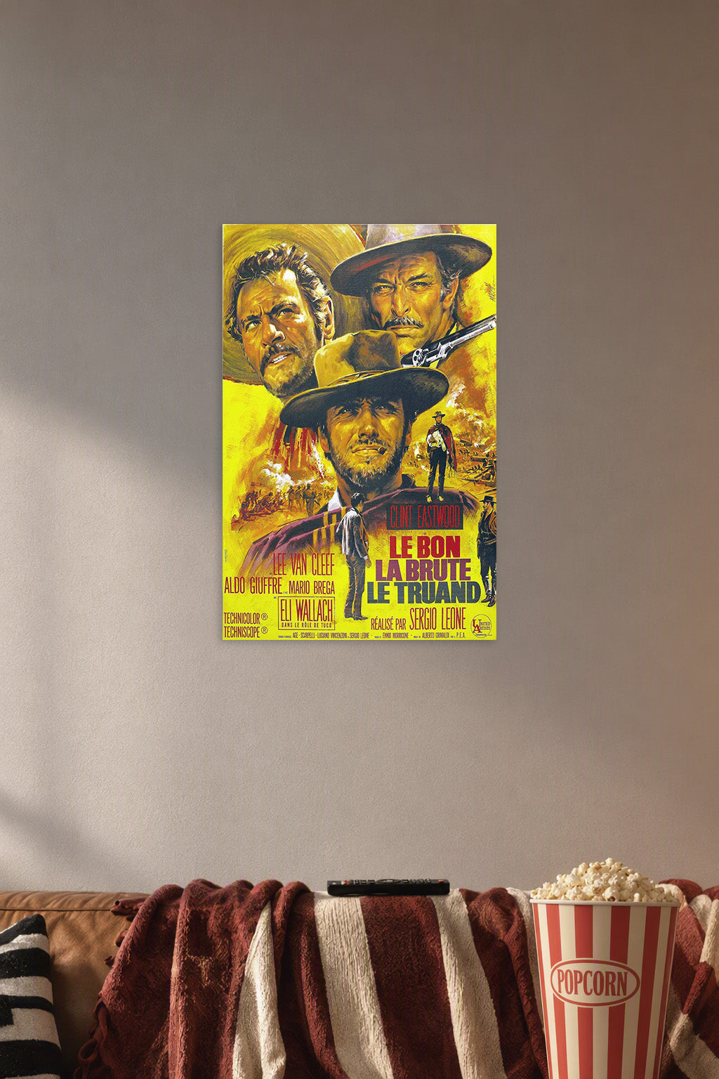 The Good The Bad The Ugly Movie Poster in a cozy movie room above a brown sofa with popcorn.