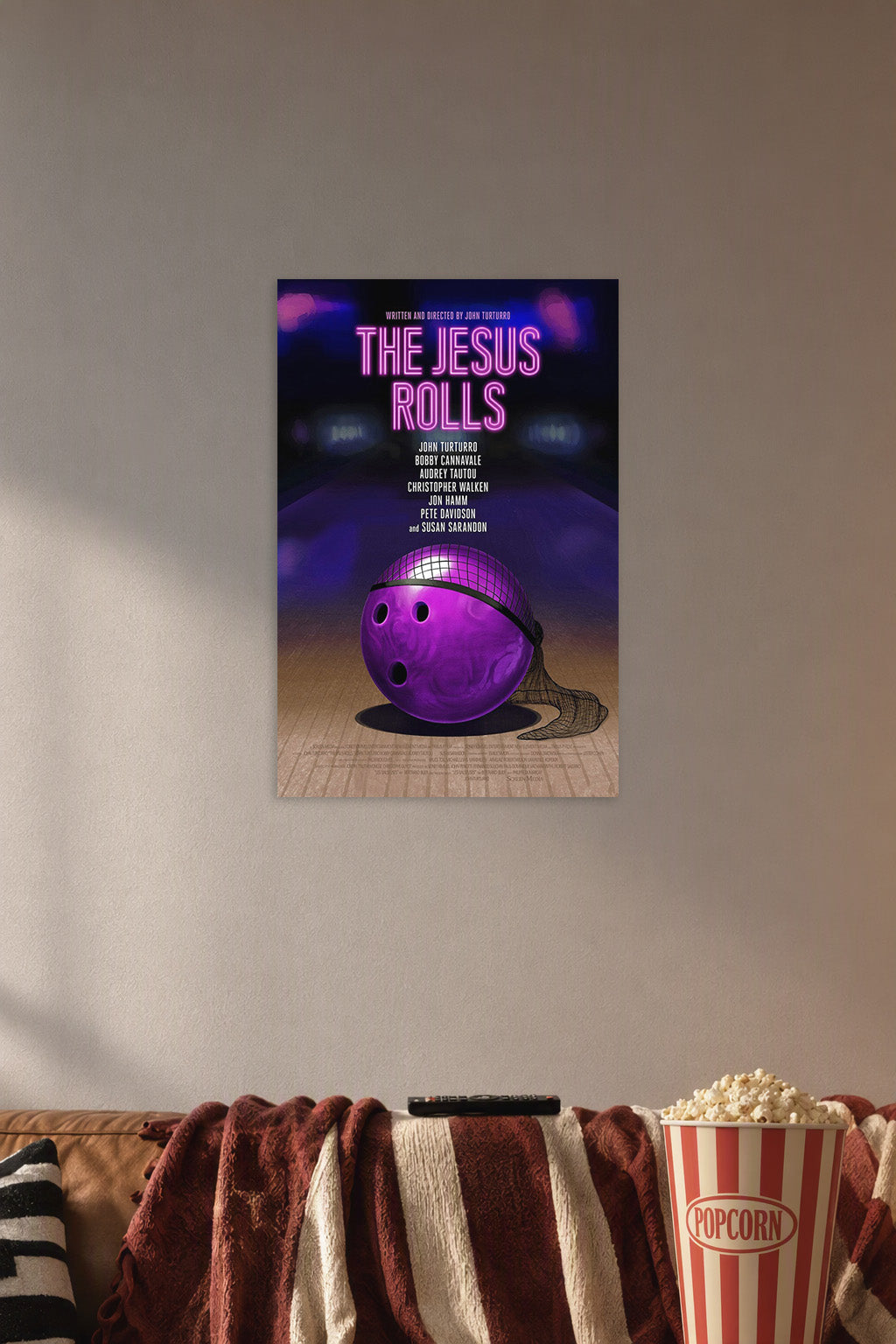 The Jesus Rolls Movie Poster in a cozy movie room above a brown sofa with popcorn.