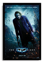 The Dark Knight framed wall art print depicts the Joker in a purple coat with sparks, rubble, and towering city buildings.