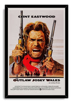The Outlaw Josey Wales framed wall art print portrays Clint Eastwood with raised revolvers, red scarf, and Western rider silhouettes.