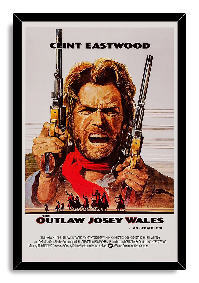 The Outlaw Josey Wales framed wall art print portrays Clint Eastwood with raised revolvers, red scarf, and Western rider silhouettes.