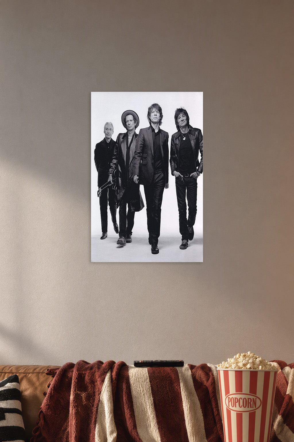 The Rolling Stones in a cozy movie room above a brown sofa with popcorn.
