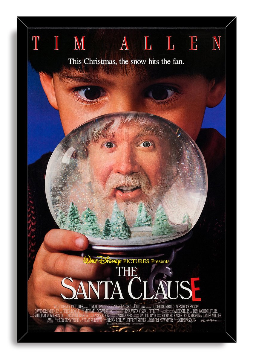 The Santa Clause framed wall art print features a close-up boy holding a snow globe with Tim Allen, snowy fir trees, and title text.