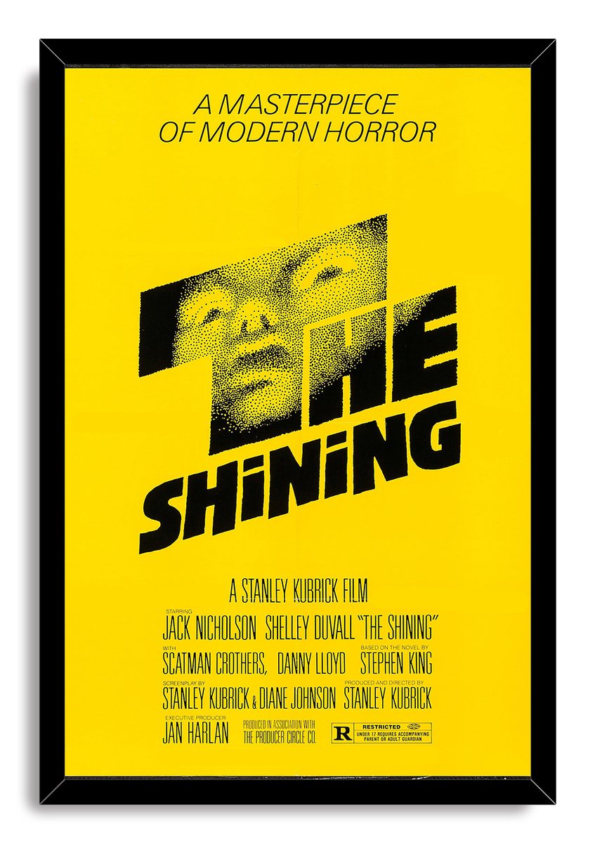 The Shining framed wall art print presents the yellow-and-black poster with a stylized male face inside a glossy black frame.