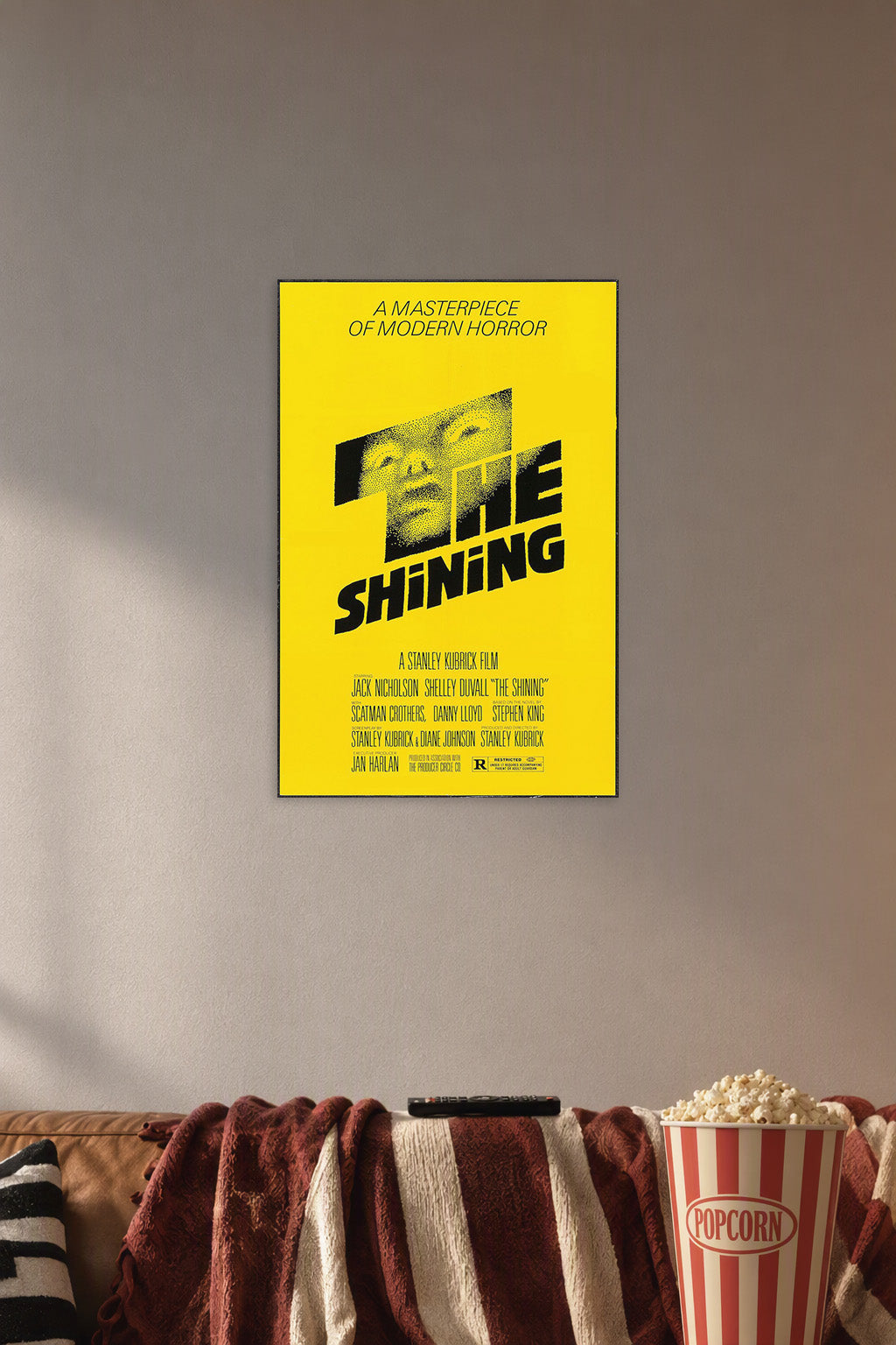 The Shining Movie Poster in a cozy movie room above a brown sofa with popcorn.