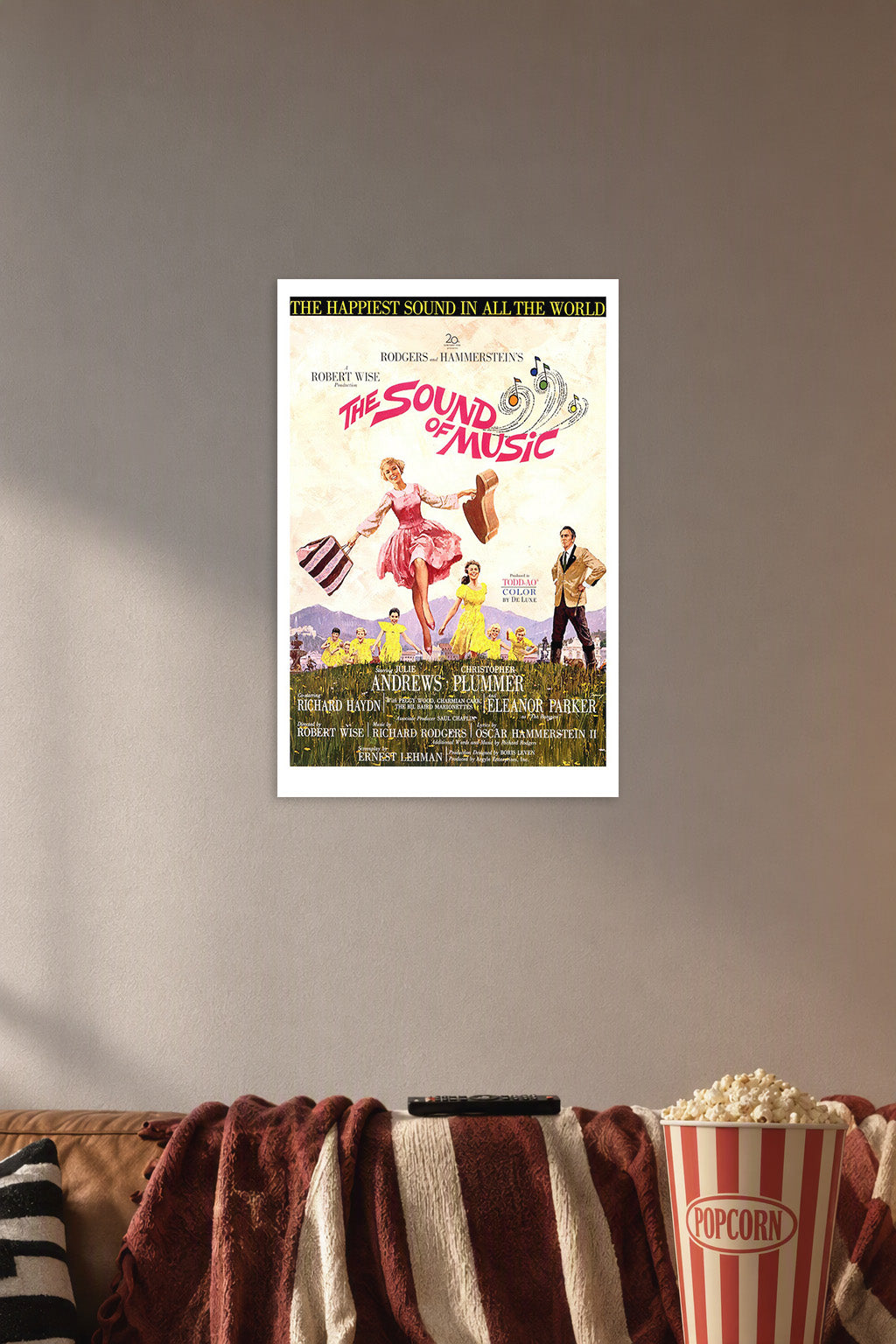 The Sound of Music Movie Poster in a cozy movie room above a brown sofa with popcorn.