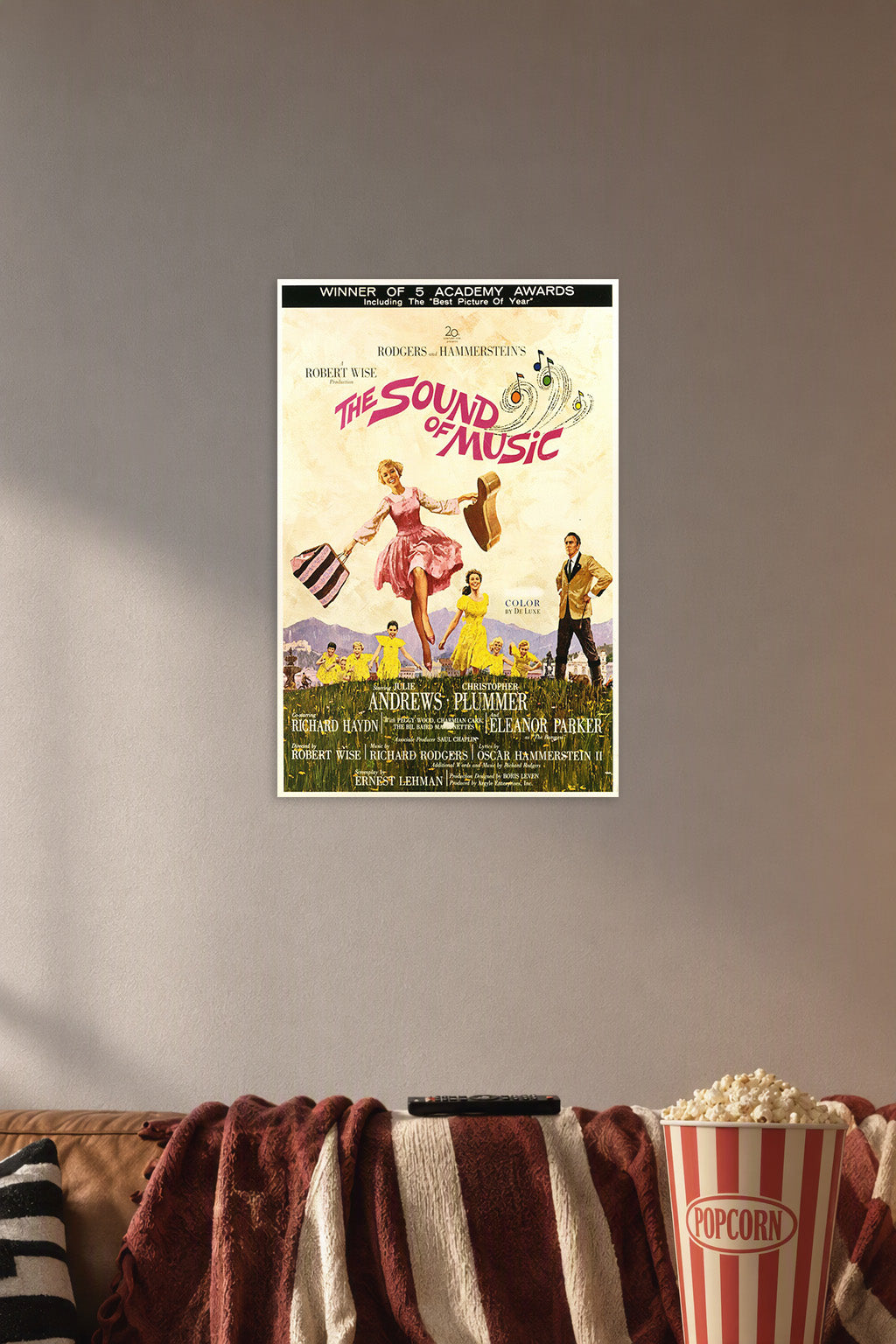 The Sound of Music Movie Poster in a cozy movie room above a brown sofa with popcorn.