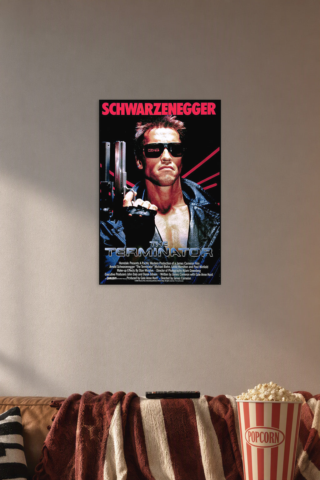 The Terminator Arnold Schwarzenegger in a cozy movie room above a brown sofa with popcorn.