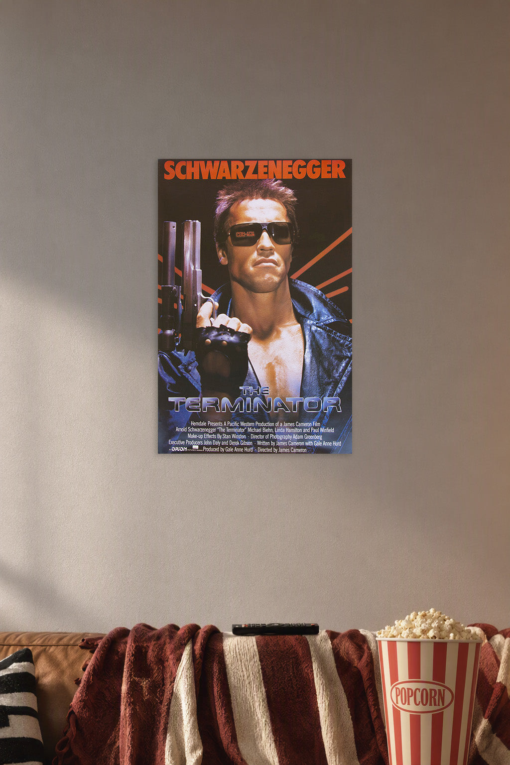 The Terminator Arnold Schwarzenegger in a cozy movie room above a brown sofa with popcorn.